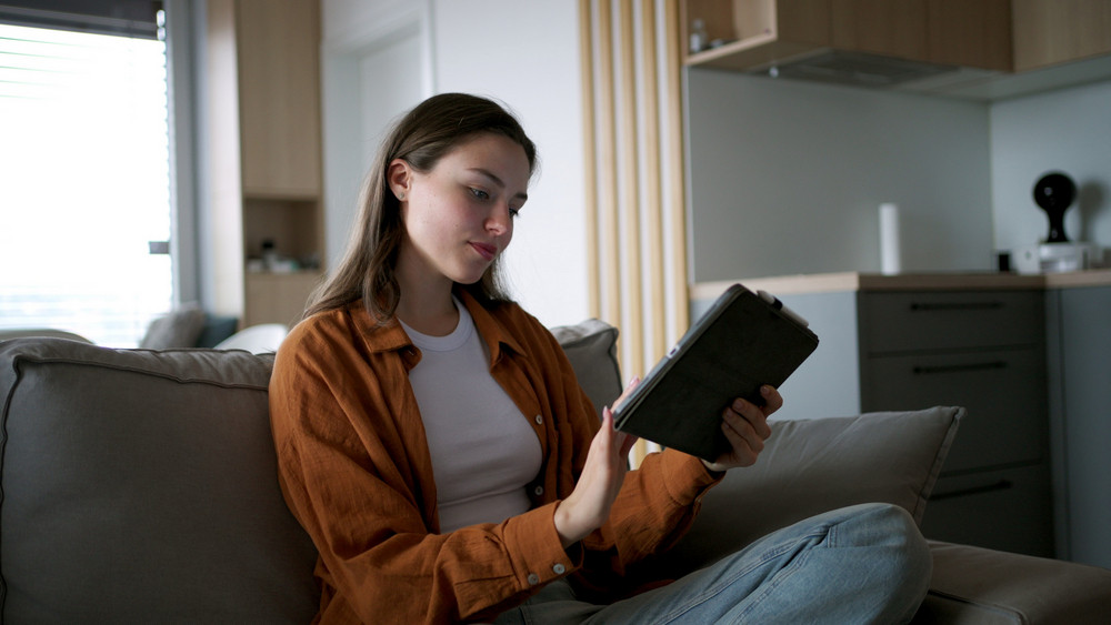 Homeowner reviewing energy usage on a tablet while considering an energy-efficient water heater repair service.